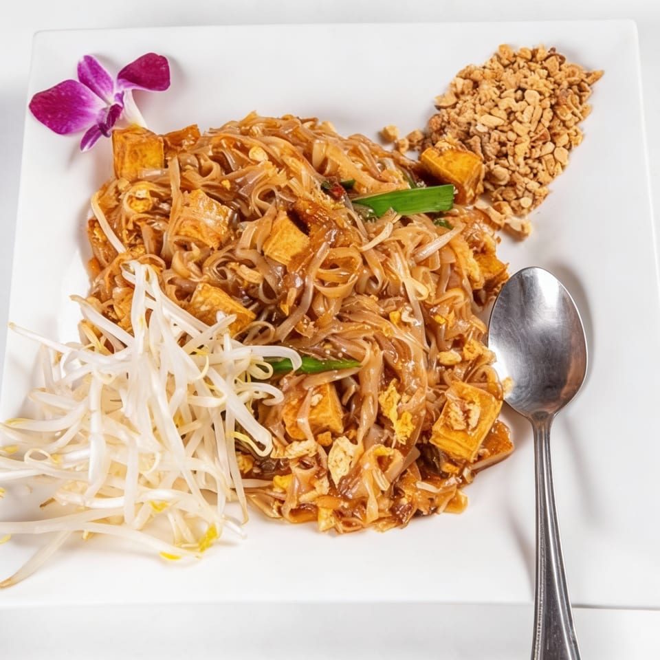Phaya Thai Halal Restaurant's Pad Thai with tofu, bean sprouts, crushed peanuts, and a purple orchid garnish.