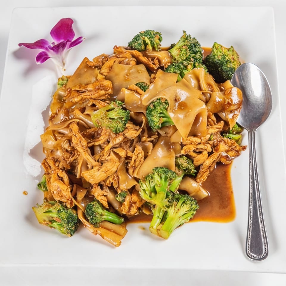 Phaya Thai Halal Restaurant's Pad See Ew with chicken and broccoli, garnished with an orchid.